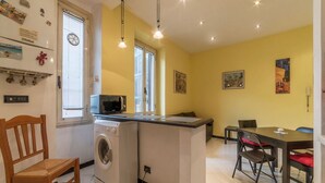Una cocina compacta equipada con lavadora, microondas y comedor con mesa y sillas.