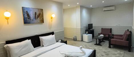 Habitación de hotel con una cama grande, un escritorio, una silla y un cuadro en la pared.