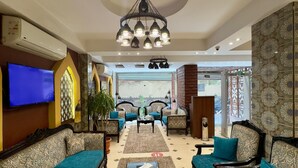 A spacious lobby with a chandelier, sofas, a coffee table, and a TV. - New Star Zamalek Hotel (Cairo)