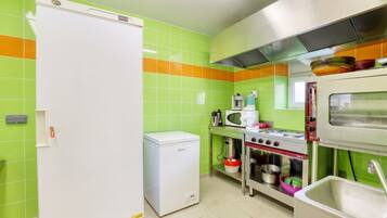 A kitchen with a refrigerator, microwave, stove, and sink.