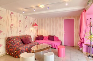 Un salon moderne avec un canapé, une table basse en verre et une porte rose.