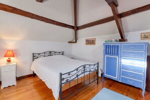 A bedroom with a single bed, a nightstand with a lamp, a dresser, and wooden beams on the ceiling. - Homerez - House near Le Bouffay (Le Bouffay)