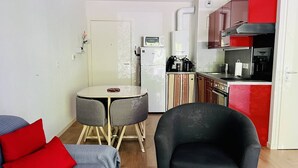 Ein kompakter Wohnraum mit Küchenzeile, einem Essbereich mit Tisch und Stühlen sowie einer Sitzecke mit Sofa und Sesseln.