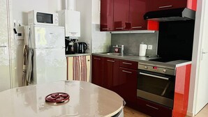 Eine kleine Küche mit Kühlschrank, Mikrowelle, Herd und Spüle.