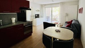 Eine kompakte Wohnung mit Küchenzeile, Essbereich und Wohnzimmer mit Sofa und Fernseher.