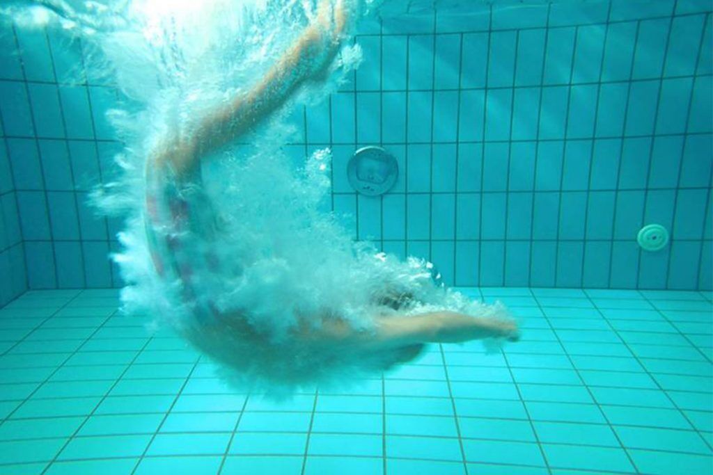An underwater view of a swimming pool with grid lines on the floor and walls.