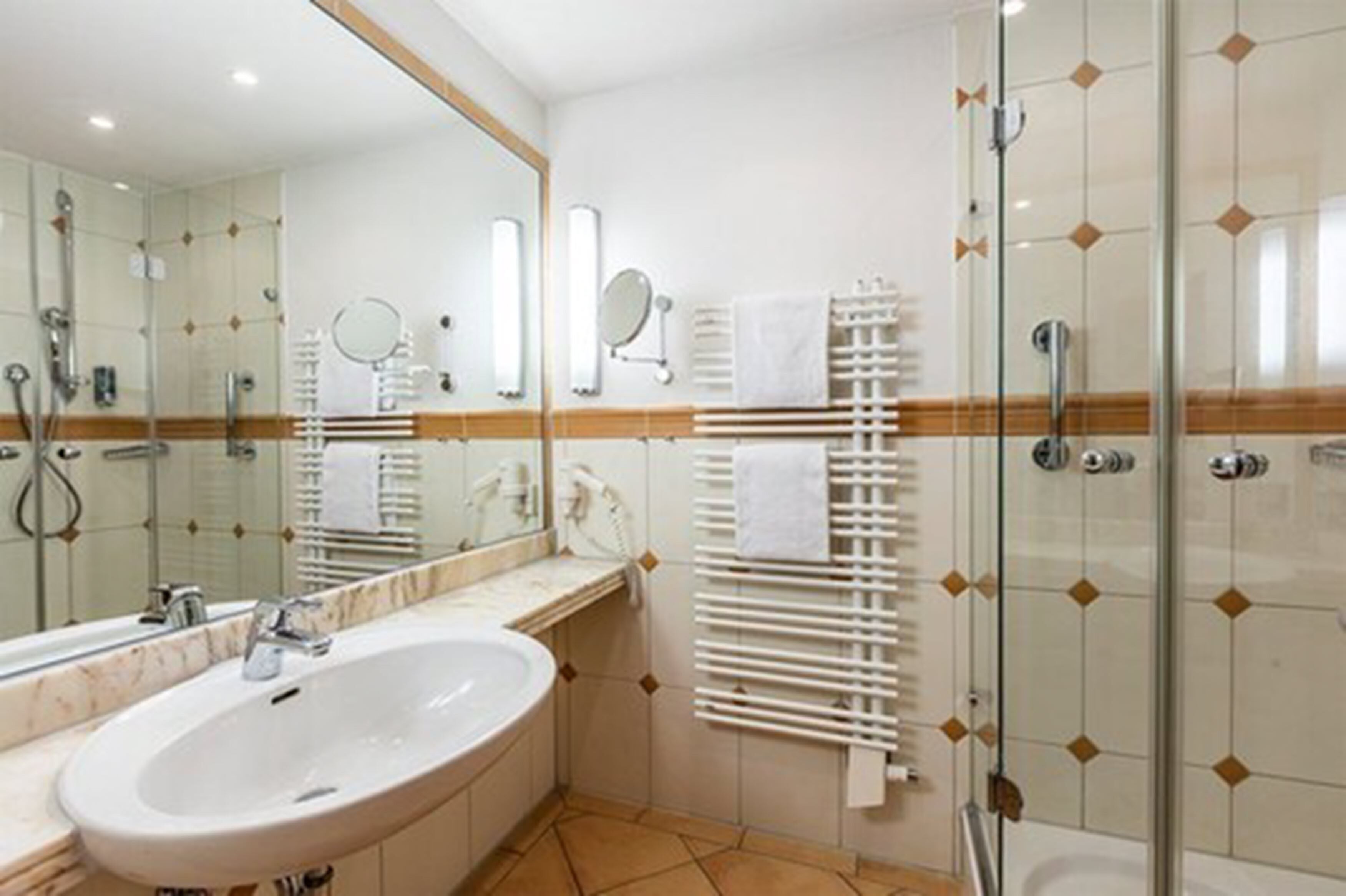 A modern bathroom with a large sink, mirror, and glass shower enclosure.