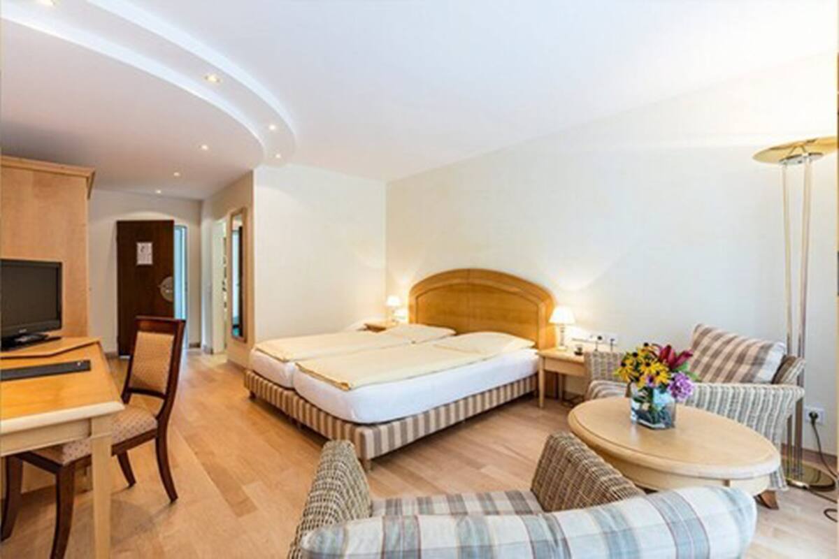 Une chambre d’hôtel comprenant un lit, un bureau avec une chaise, une petite table ronde et un téléviseur.