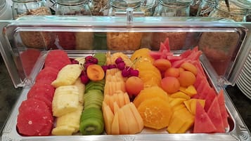 A buffet with a variety of fruits and vegetables, including watermelon, cantaloupe, and oranges.