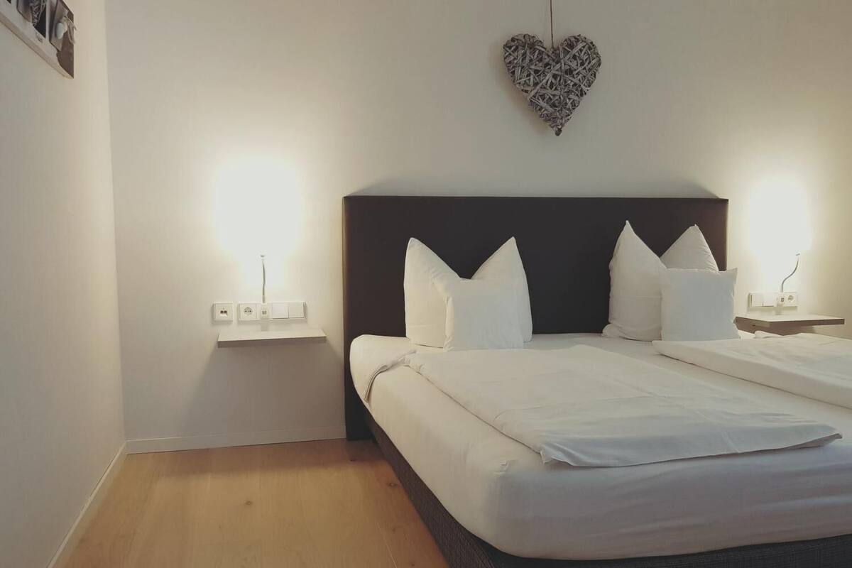 Une chambre d’hôtel avec un grand lit, deux tables de chevet et un élément décoratif en forme de cœur sur le mur.