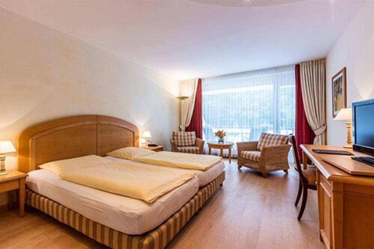 Une chambre d’hôtel avec un grand lit, deux tables de chevet, un bureau, une chaise et un téléviseur.