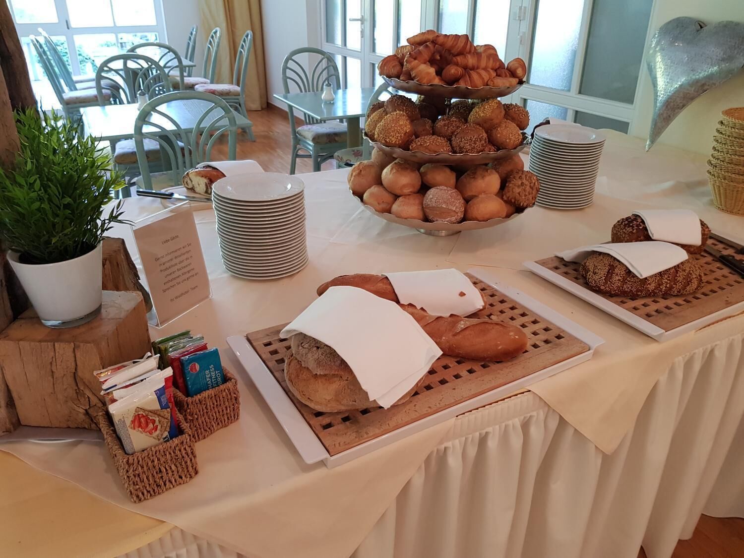 Un buffet de petit-déjeuner comprenant du pain, des viennoiseries et un panneau d’information.