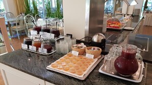 Een buffetopstelling met diverse etens- en drinkmogelijkheden, waaronder potjes met sauzen, een schaal met gebakjes en een karaf met een rood drankje.