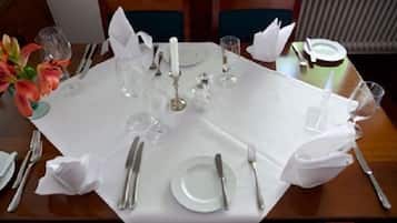A dining table set for a meal with white tablecloth, plates, cutlery, and glassware.
