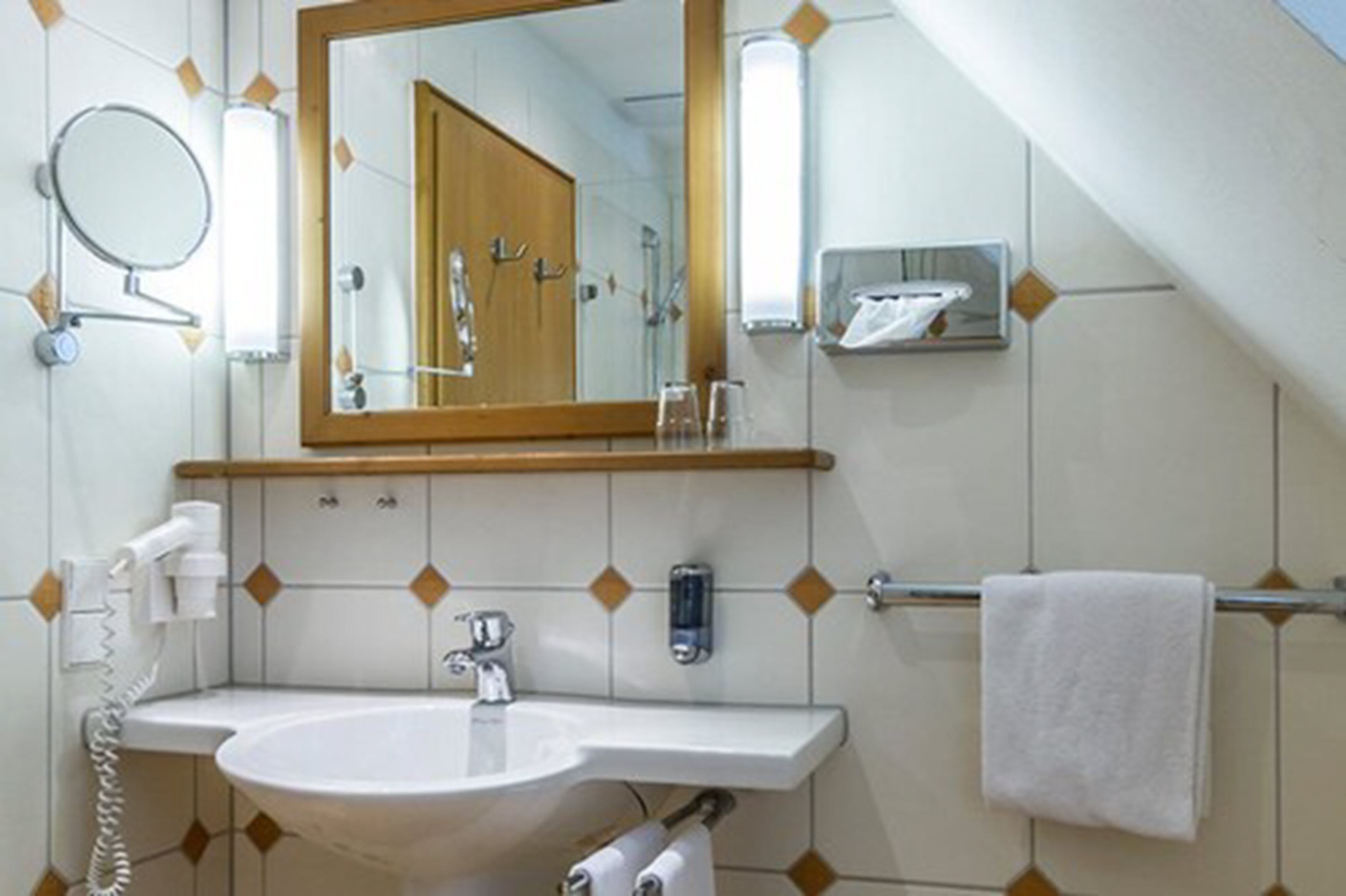 A bathroom with a sink, mirror, towel rack, and a shower area.