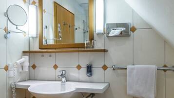 A bathroom with a sink, mirror, towel rack, and a shower area.