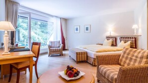 Hotelkamer met een bed, een bureau, een stoel, een bank en een tafel met fruit.