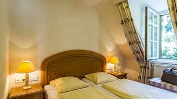 Een slaapkamer met twee bedden, een houten hoofdbord, nachtlampjes en een raam met gordijnen.