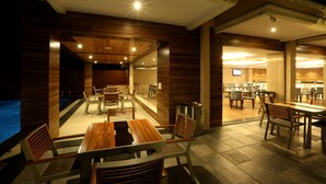 A restaurant with wooden furniture and a pool area. - Resort The Lohias (Candolim)