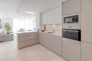 A modern kitchen with integrated appliances, a central island, and a dining area with a view.