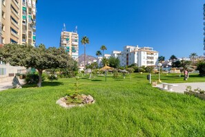A grassy park area with trees and a white bench.