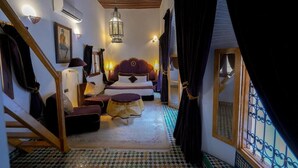 A bedroom with a bed, a sofa, a small table, and a staircase. - Riad Sahraui (Fes)