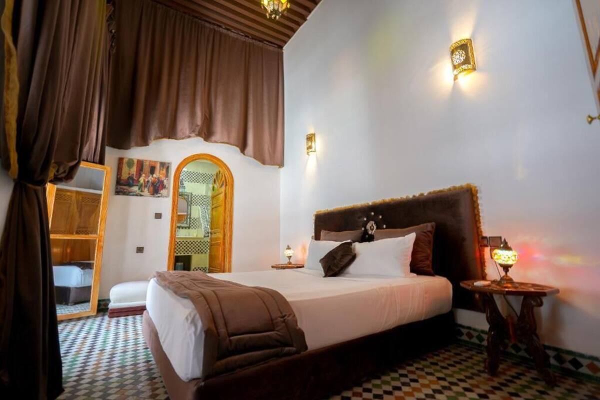 Quarto com uma cama grande, mesa de cabeceira, abajur e vista para uma varanda.