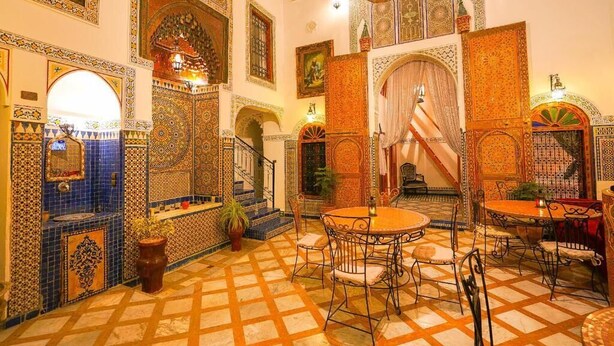 A traditional Moroccan interior with tiled floors, ornate arches, and a central seating area. - Riad Sahraui (Fes)