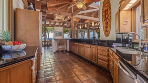 A spacious kitchen with wooden cabinets, a black countertop, and a ceiling fan. - Fabulous Ocean Views with Mauna Kea Resort Access (Waimea)