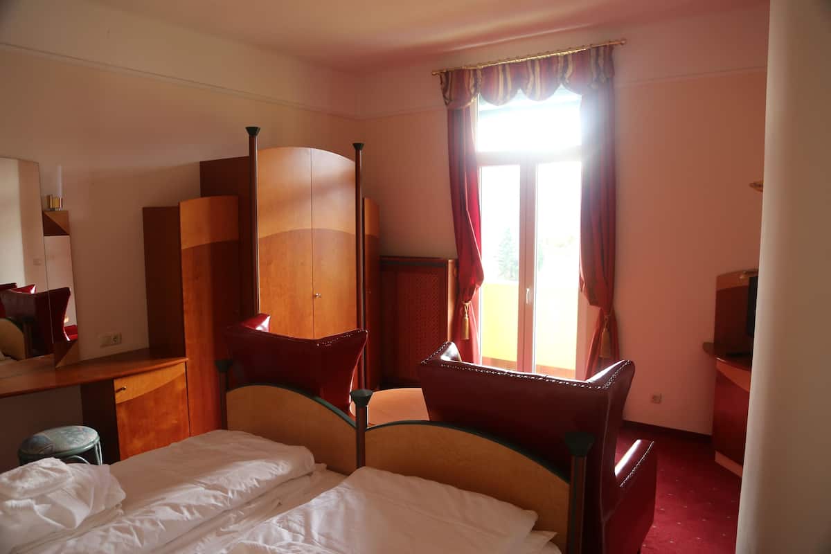 A hotel room with a bed, a desk, a chair, and a window with curtains.
