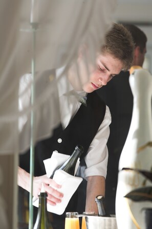 A person pouring a drink from a bottle into a glass. - Hotel Kaiser Franz Josef (Millstatt)