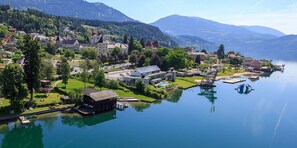 A lakeside town with buildings, a dock, and a boat. - Hotel Kaiser Franz Josef (Millstatt)