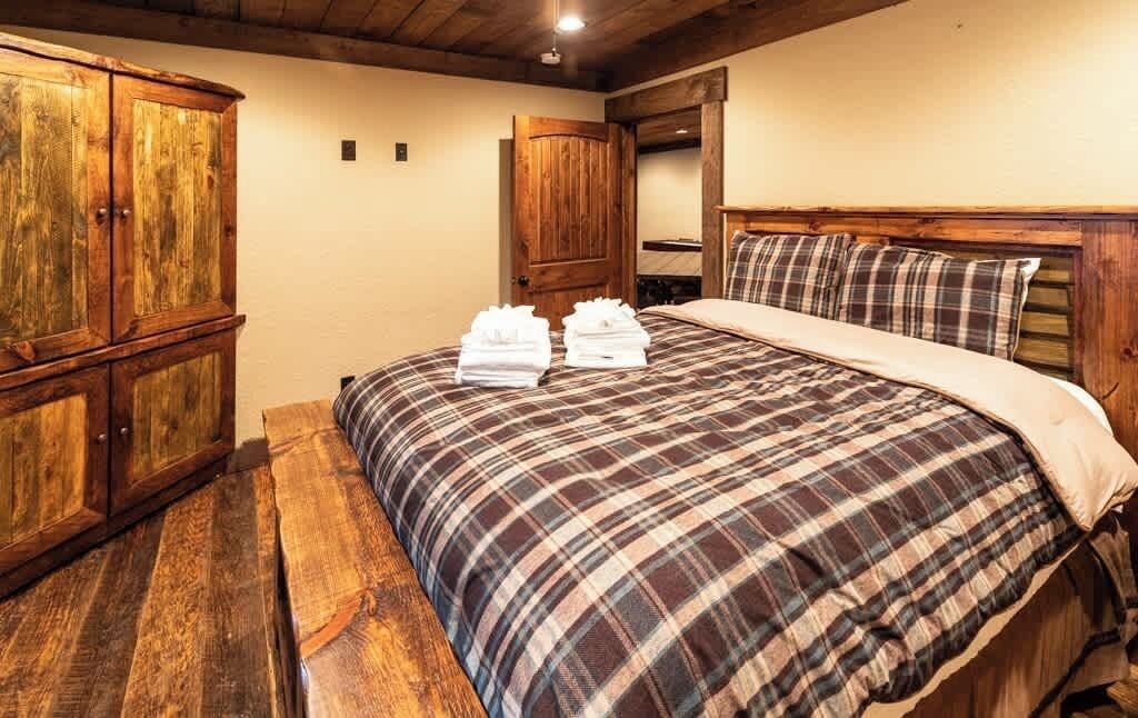 A bedroom with a wooden bed, a wooden wardrobe, and a bench.