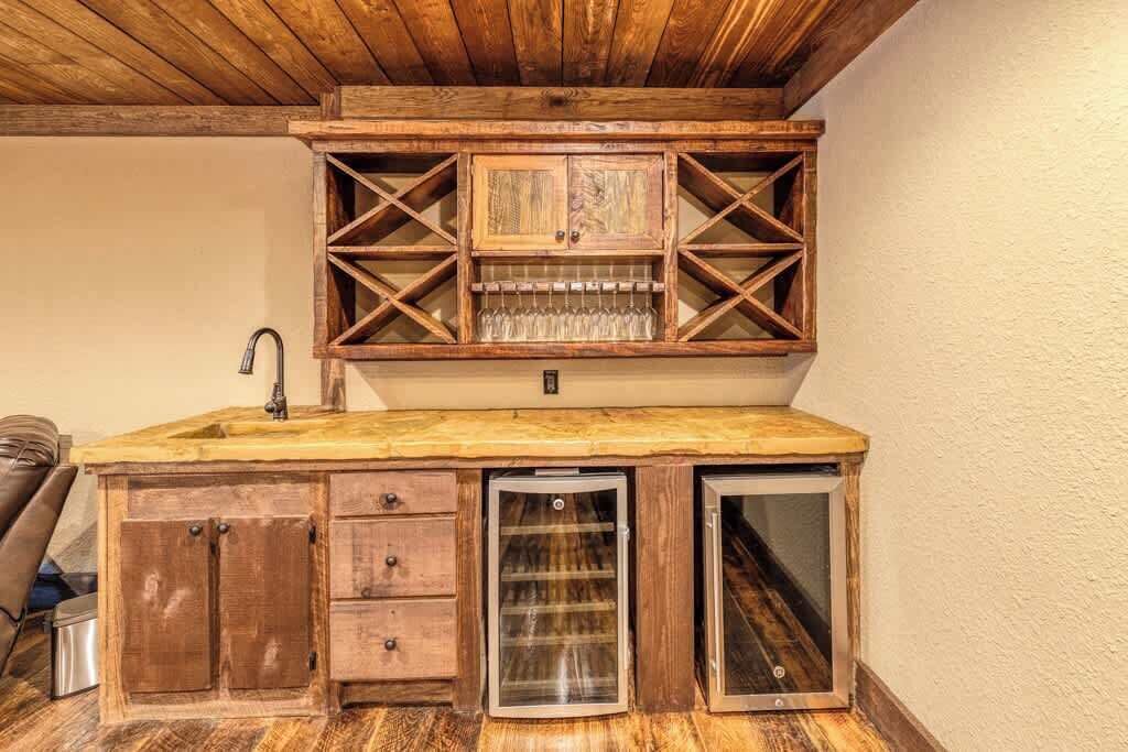 Eine kleine Küche mit Holzsärchen, einem integrierten Weinkühlschrank, einer Spüle und einem Kühlschrank.
