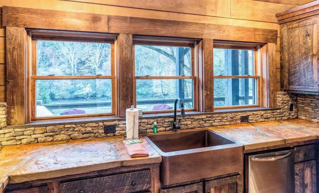 A kitchen with a stone countertop, a sink, and wooden cabinets.