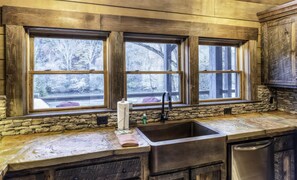 Enjoy cooking in this kitchen with a large window offering a view of the surrounding landscape, featuring an oven and dishwasher.