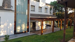 A modern house with a covered patio, a stone wall, and a well-maintained lawn. - Spectacular villa with private pool and large spaces  (Caldes de Montbui)