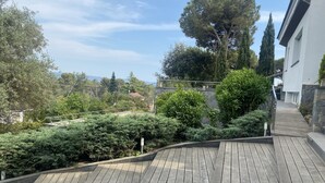 A wooden deck with a stone border, surrounded by lush greenery and trees. - Spectacular villa with private pool and large spaces  (Caldes de Montbui)