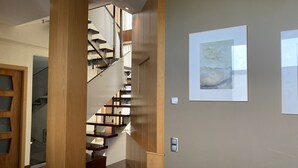 A modern interior with a wooden staircase, a glass door, and a framed abstract painting on the wall. - Spectacular villa with private pool and large spaces  (Caldes de Montbui)