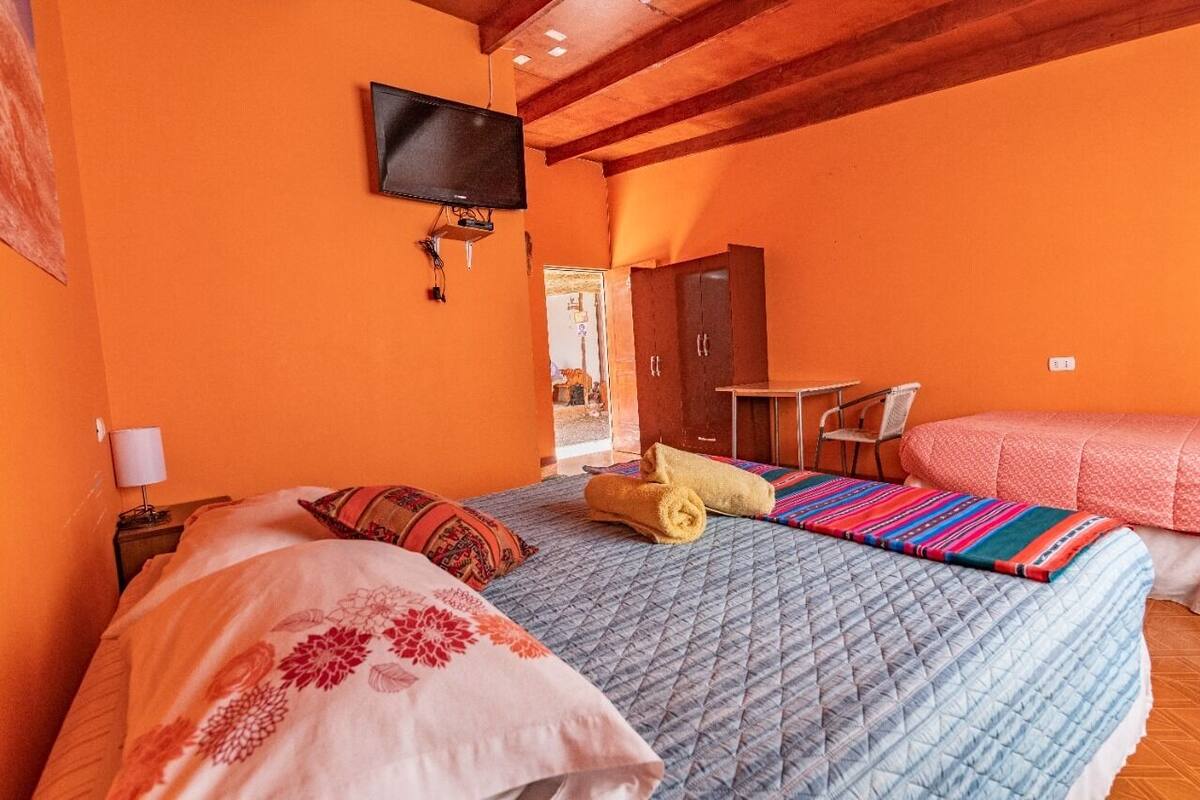 Ein Schlafzimmer mit Bett, Wandfernseher, Schreibtisch und Stuhl.