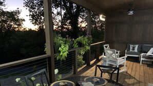 A wooden deck with outdoor furniture, including a table and chairs, surrounded by greenery and a view of the landscape. - Discover Your Perfect Getaway: Cottage in the Heart of Horse & Bourbon Country! (Midway)