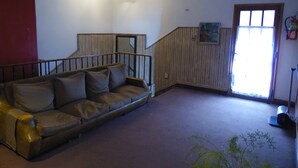 A living room with a brown leather sofa, a wooden staircase, and a window with a view. - Hotel San Francisco (San Juan)