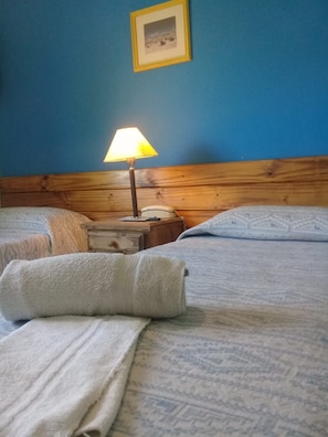 A hotel room with two beds, a wooden headboard, a bedside lamp, a telephone, and a framed picture on the wall. - Hotel San Francisco (San Juan)