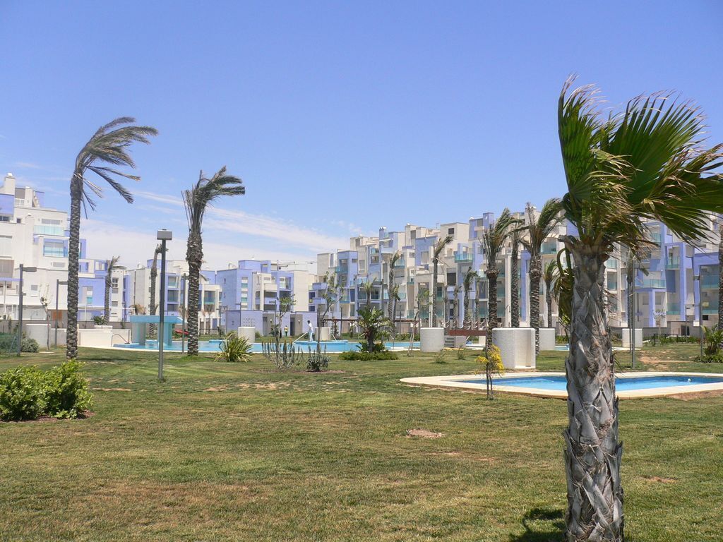 A residential area with modern buildings, a swimming pool, and palm trees.