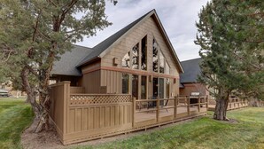 A cabin with a wooden deck, large windows, and a sloped roof. - Forest Ridge 2 Bedroom Home by RedAwning (Redmond)