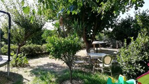 Een tuin met een tafel en stoelen, omringd door bomen en begroeiing.