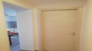 Een gesloten deur in een kamer met een lichtgekleurde vloer en witte muren.