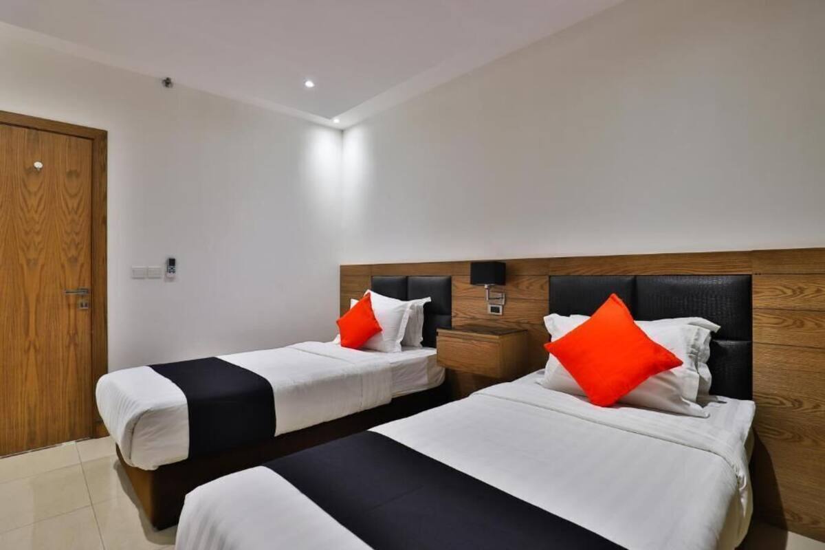 A hotel room with two beds, a wooden headboard, a nightstand, and a door.