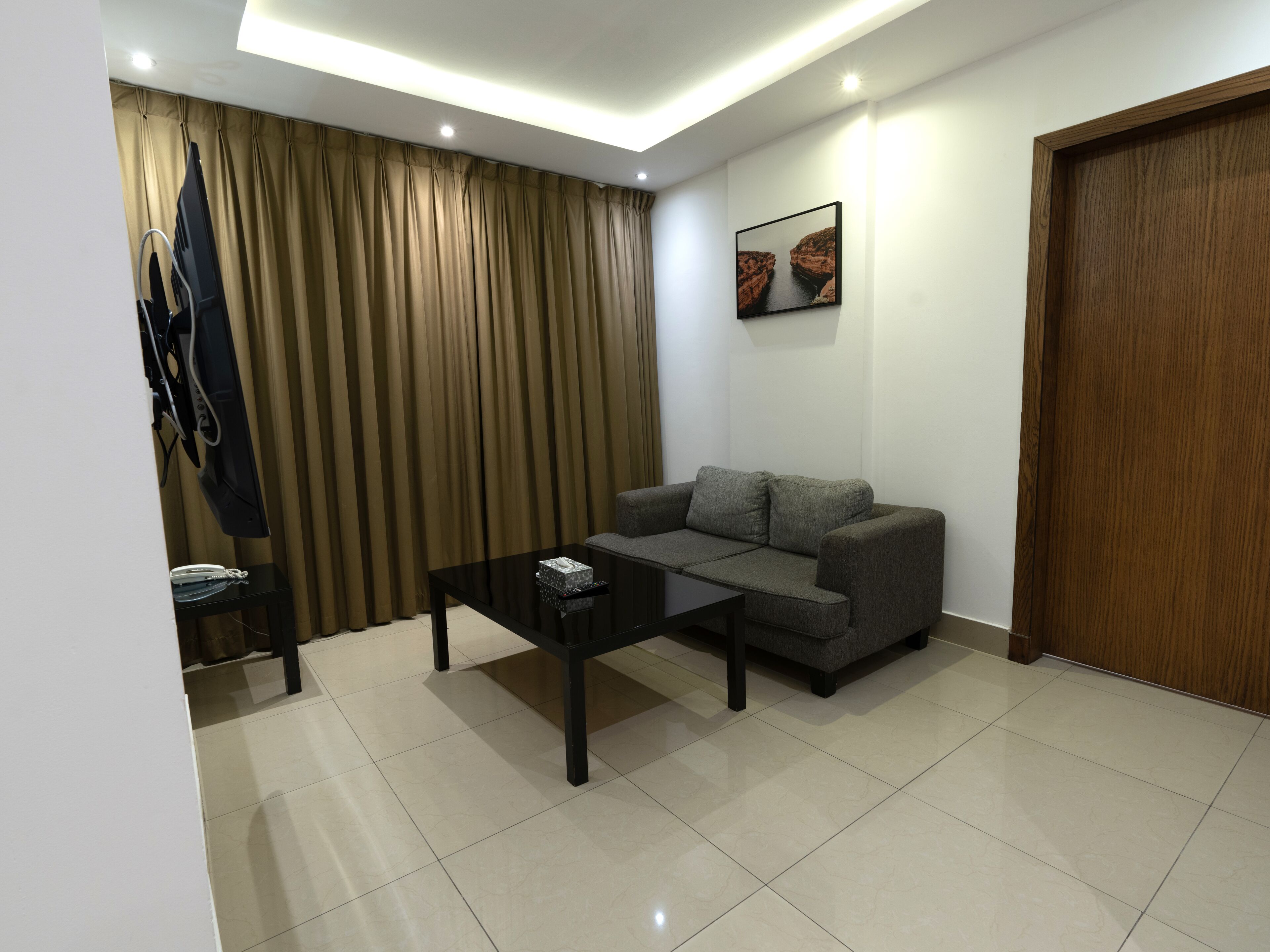 A modern living room with a grey sofa, a black coffee table, and a wooden door.