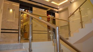 Un interior de hotel moderno con suelo de mármol, barandillas de vidrio y una escalera bien iluminada.